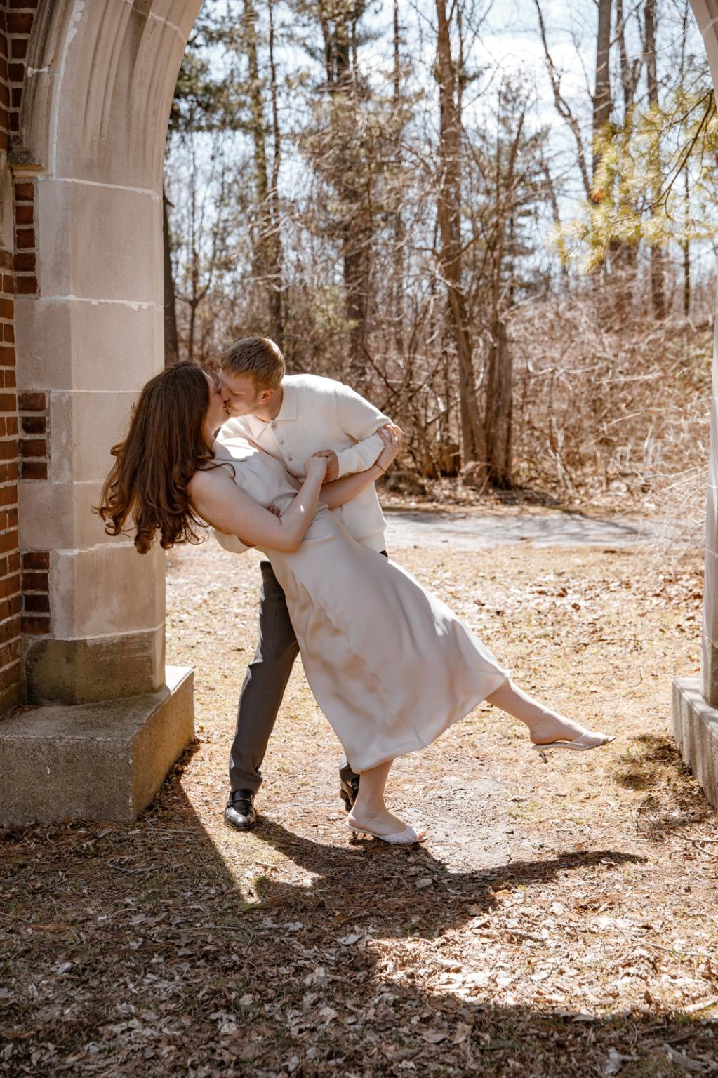 Maria and Cole kissing under a stone arch